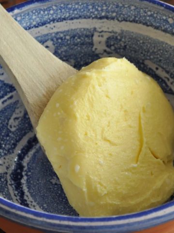 Homemade vanilla butter in a blue bowl sitting on a wooden spoon (1)