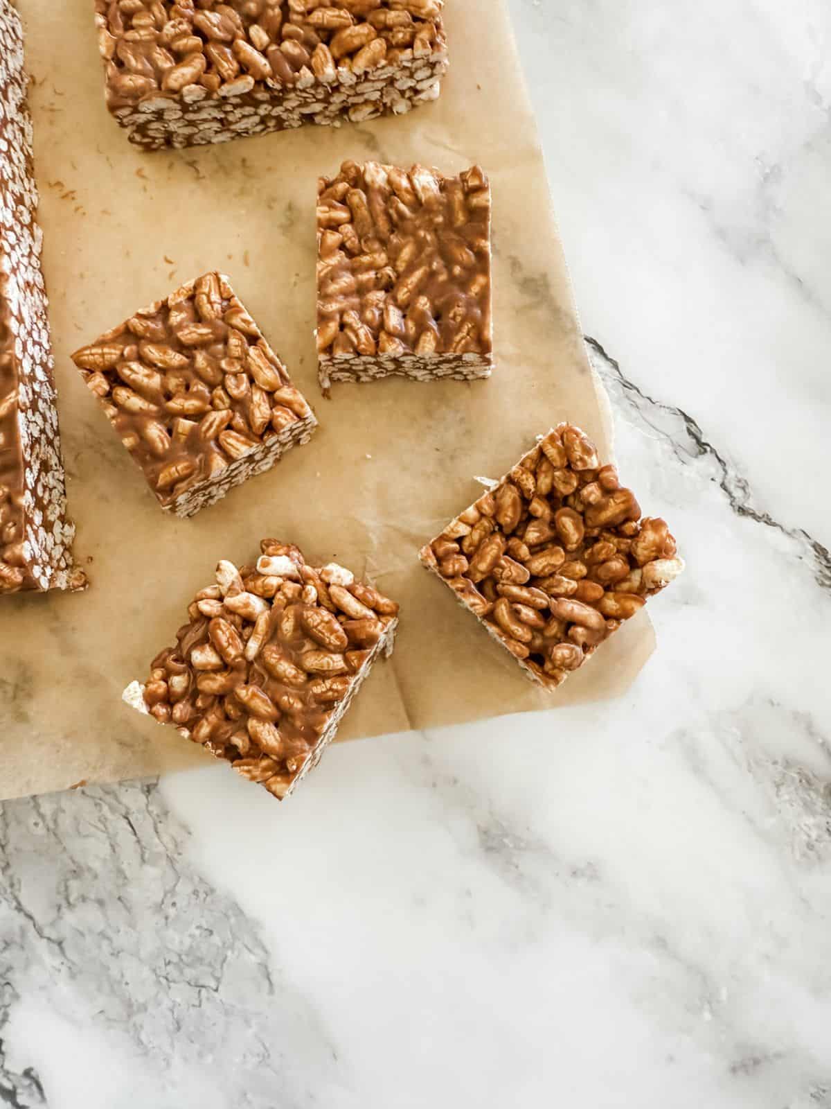 Four squares of mars bar slice on baking paper