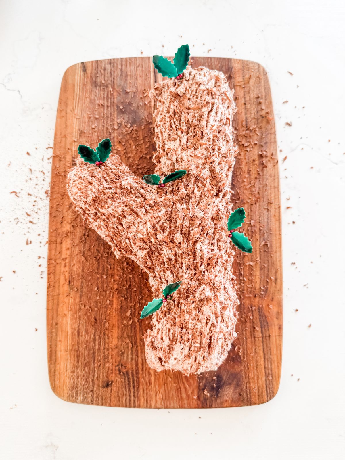 Chocolate biscuit cake shaped like tree branch on wooden board.