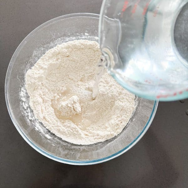 Adding water to flour, yeast and salt to make ciabatta rolls