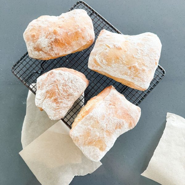 Ciabatta rolls cooling on a wire rack fresh from the oven