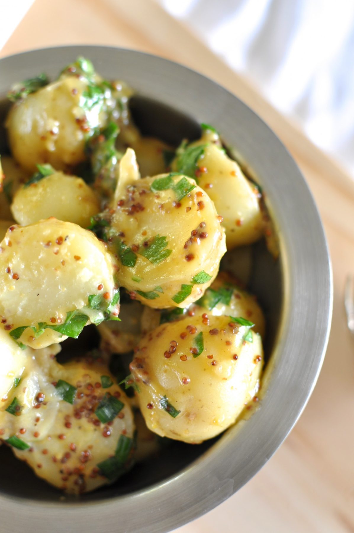 Dairy-free potato salad made with olive oil and grain mustard in a bowl sprinkled with parsley