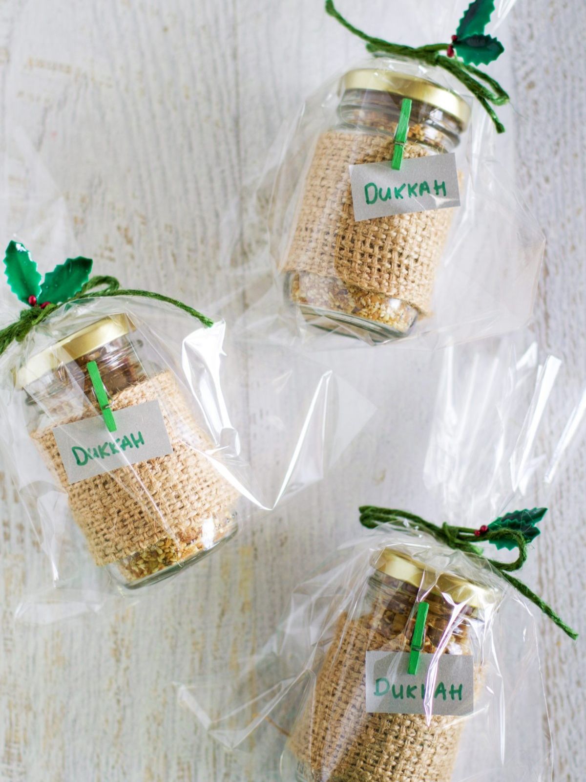 3 jars of macadamia dukkah wrapped in celophane and lying on a white bench top.
