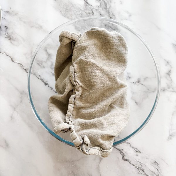 Dough wrapped in a tea towel in a glass bowl