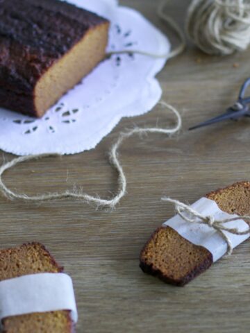 Gingerbread loaf cake with two slices wrapped in a piece of paper with a twine bow.
