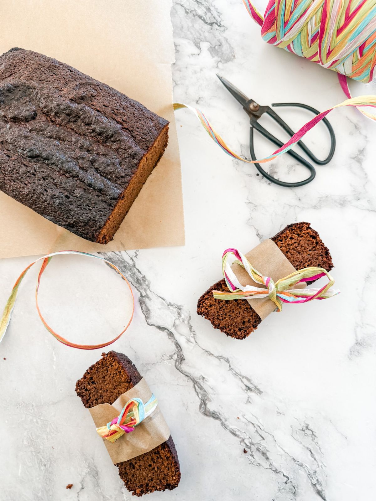 Gluten-Free Gingerbread Loaf Cake - loaf & 2 slices wrapped in paper and rainbow twine. 
