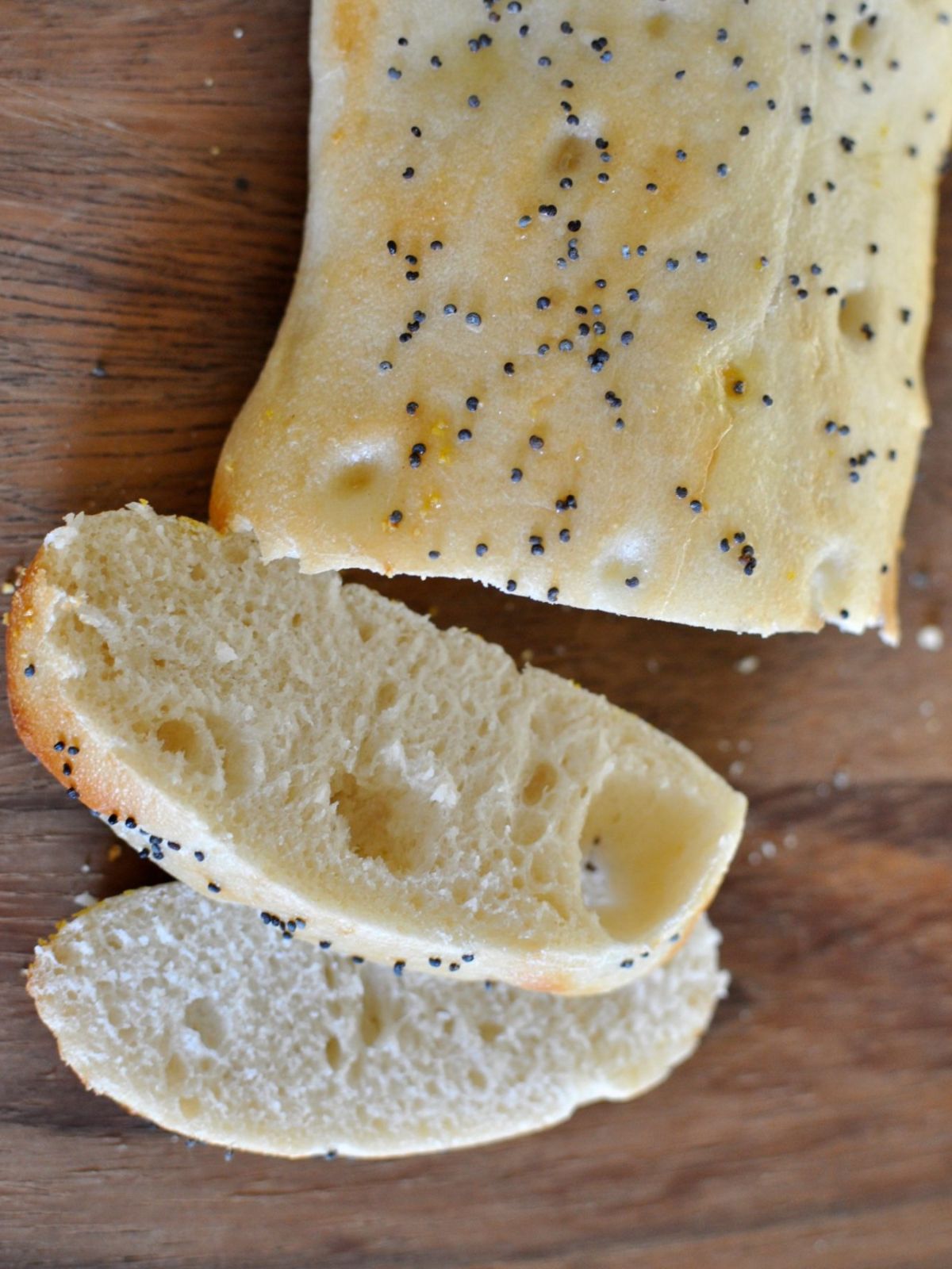 Loaf of turkish bread on wooden chopping board with 2 slices cut. 