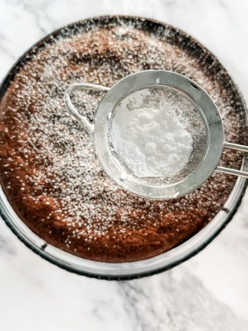 Sprinkling icing sugar on a flourless chocolate cake