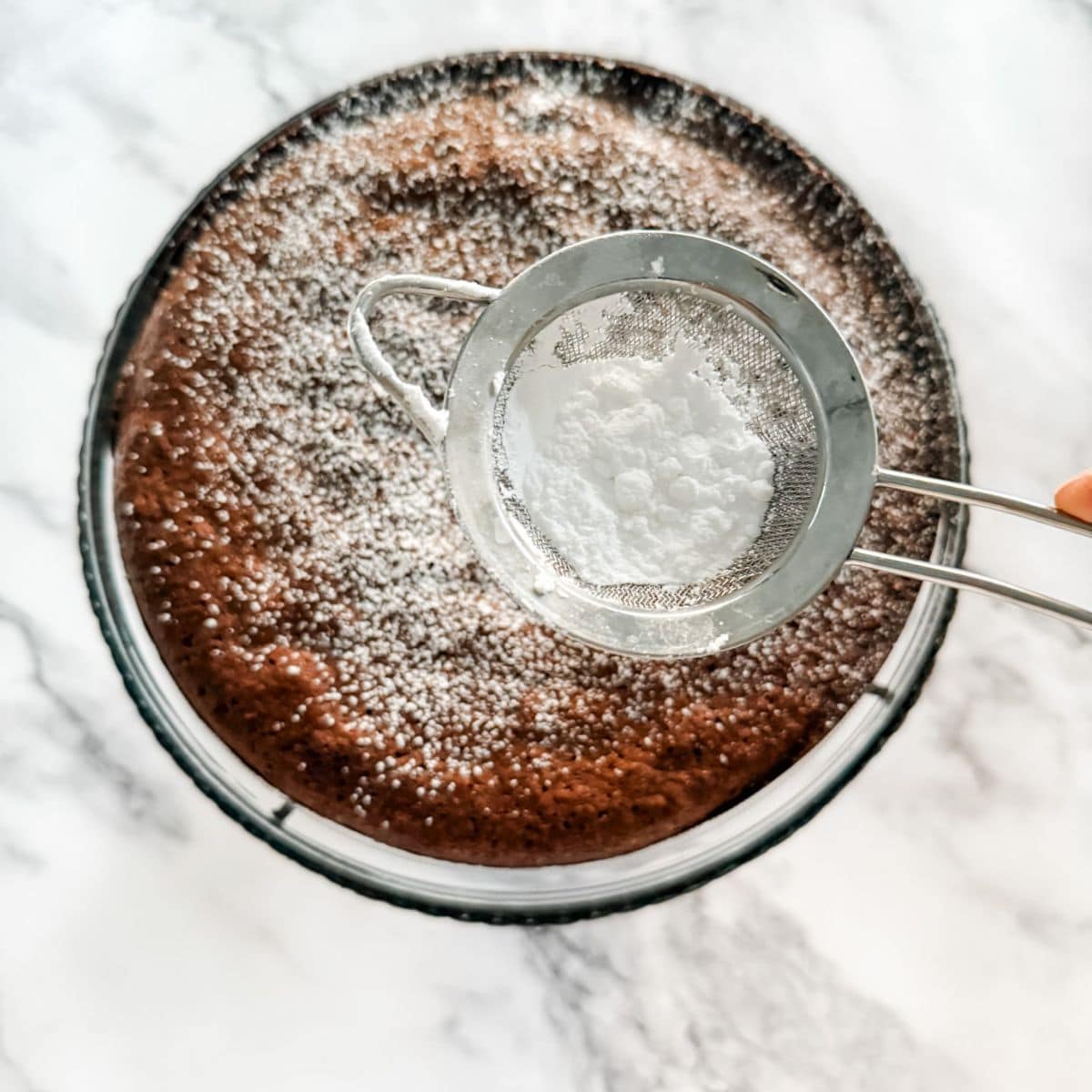 Sprinkling icing sugar on a flourless chocolate cake