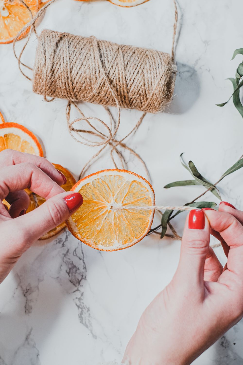 Threading dried oranges to make a dried orange garland