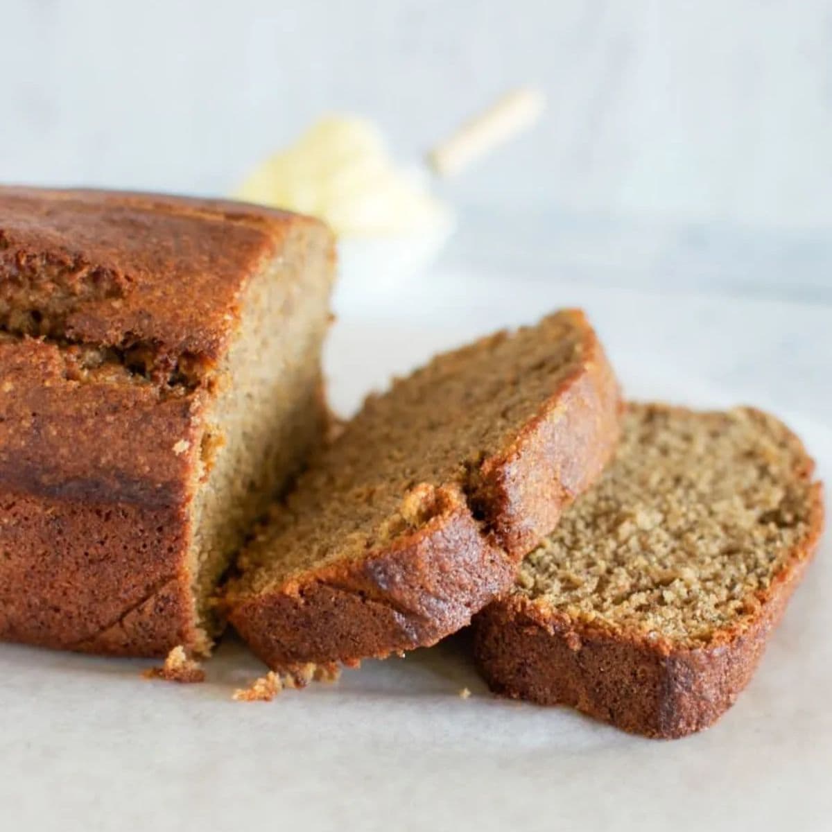Kid friendly banana bread - with two slices off the end. A little ceramic ramekin of butter in the background