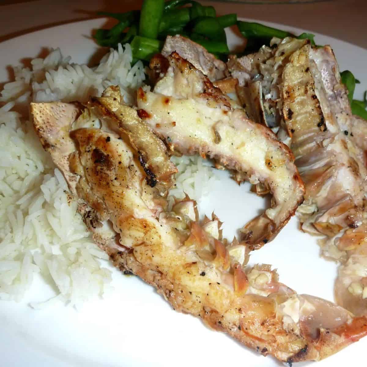 Garlic bugs on the BBQ - 3 half moreton bay bugs cooked and on a bed of rice on a white plate.