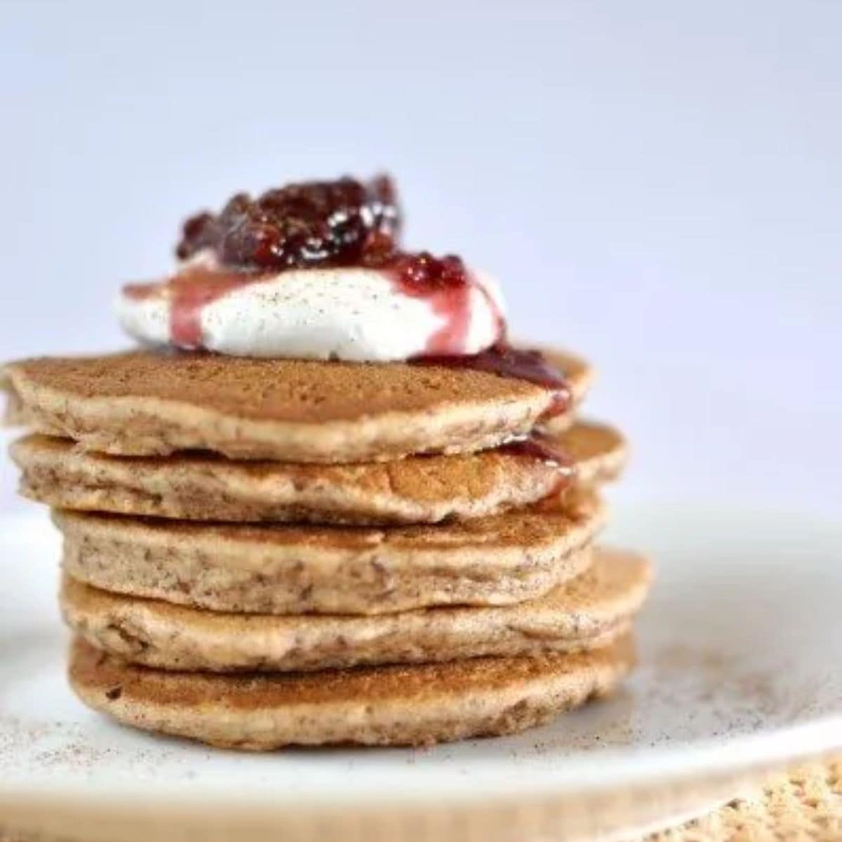 Almond and cinnamon paleo pancakes - stack of 5 pancakes topped with coconut yoghurt and berry compote.