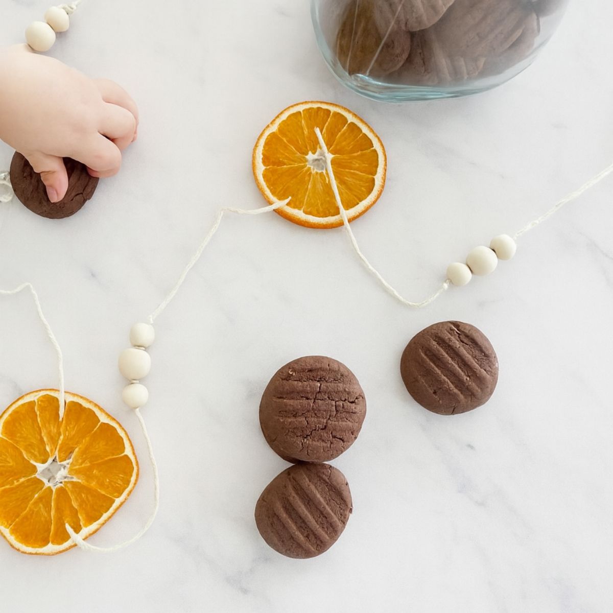 4 Chocolate shortbread Christmas Cookies on white marble benchtop with jar of cookies.