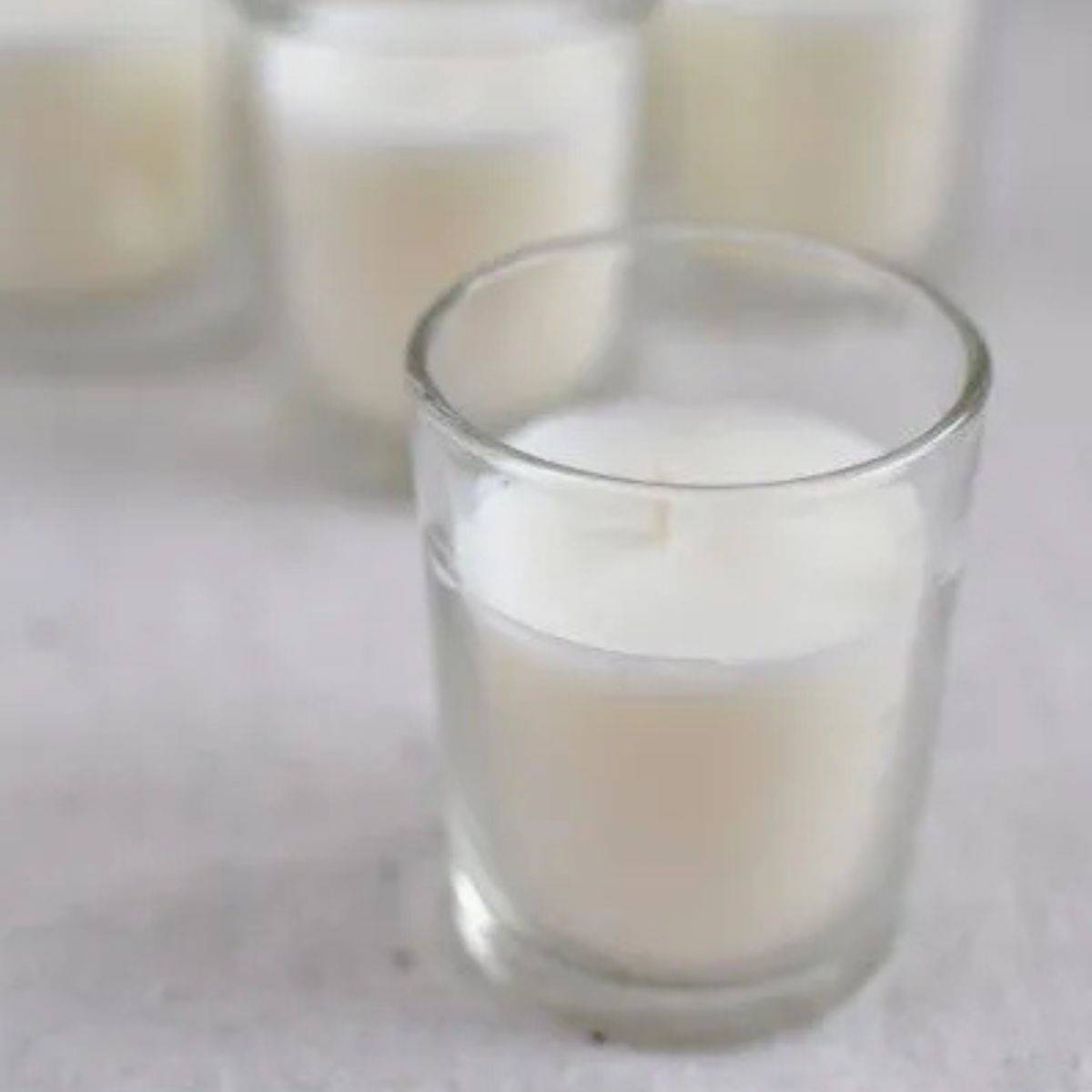 White Soy wax candle in small glass container and 3 more in the background. 