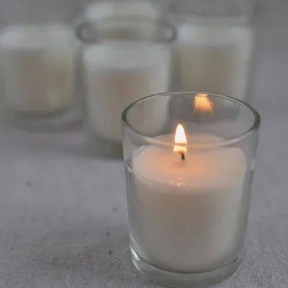 Homemade soy candle lit in a glass container.