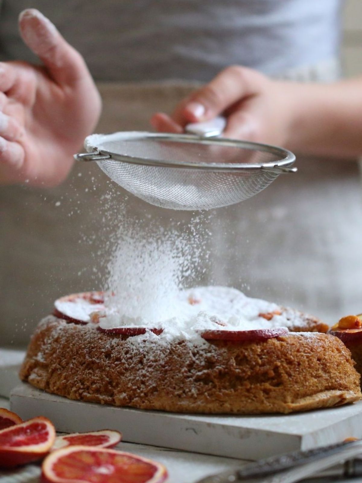 Icing sugar being dusted on a cake.
