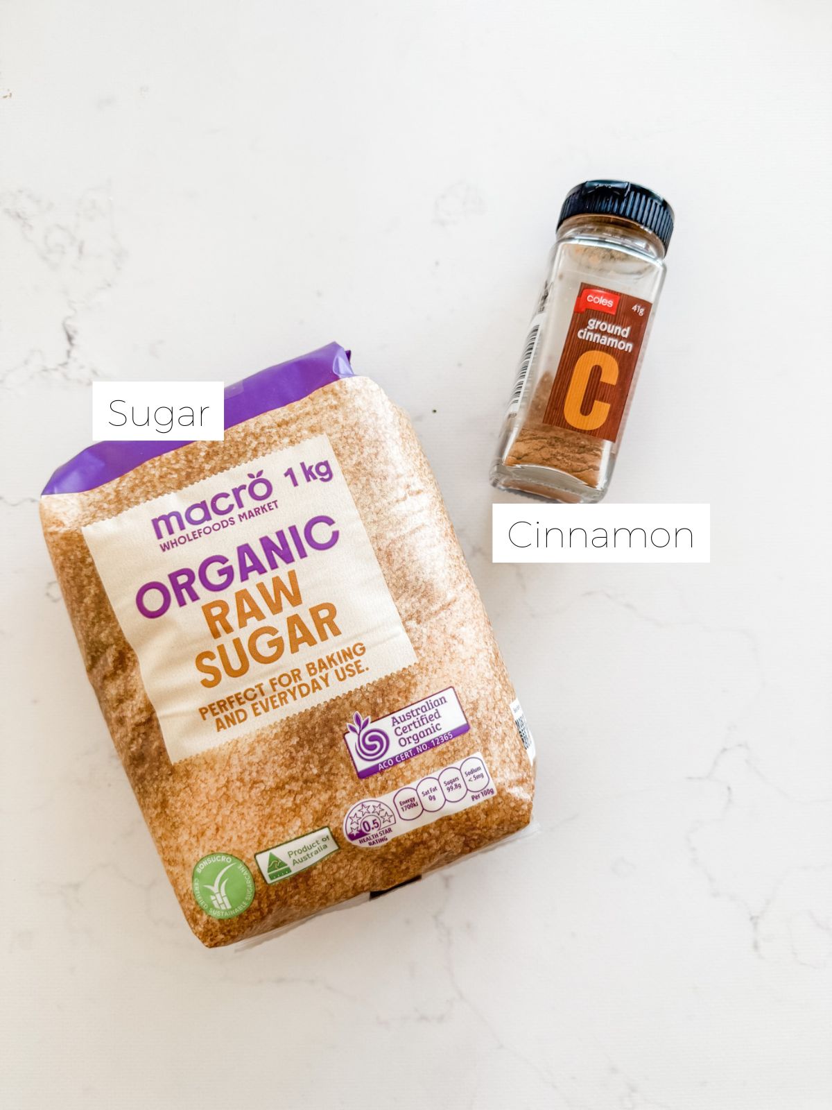 Bag of raw sugar and jar of cinnamon on white marble bench to make cinnamon sugar.