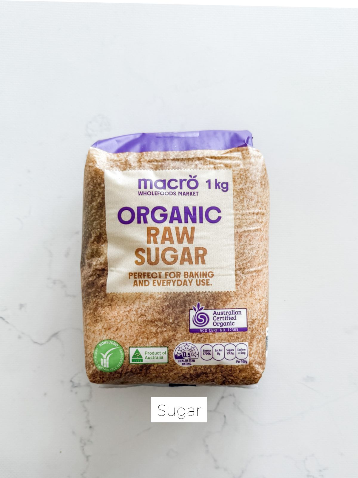 Bag of raw sugar on white marble bench.