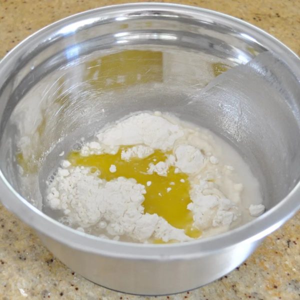 Olive oil in a silver bowl with flour and salt.