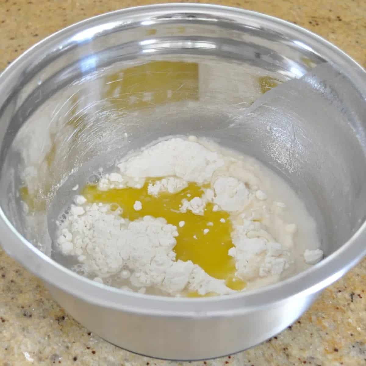 Olive oil in a silver bowl with flour and salt.