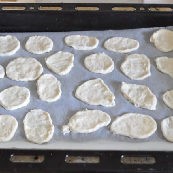 Homemade water crackers on a lined baking tray ready to go in the oven