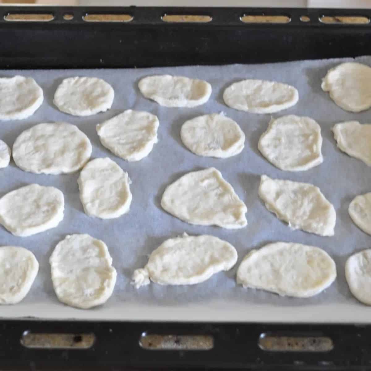 Homemade water crackers on a lined baking tray ready to go in the oven