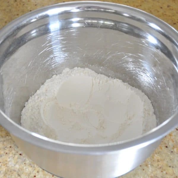 Flour and salt in a silver bowl on a kitchen bench