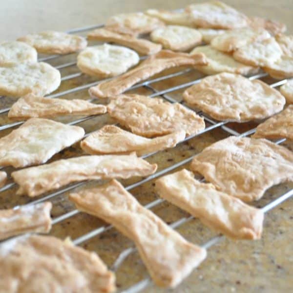 Homemade water crackers on a cooling rack on a bench
