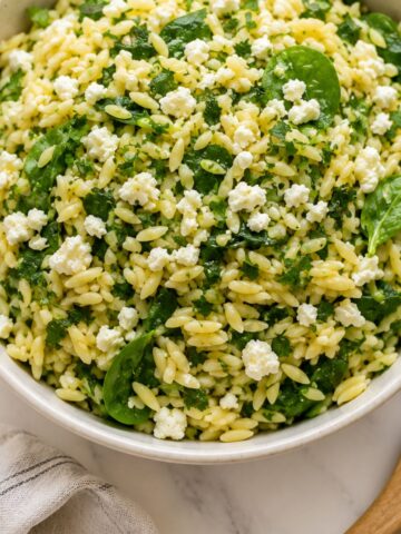 Easy Lemon Orzo (Risoni) Salad: Quick Pasta Side in a white bowl on a white marble bench top with wooden serving utensils.