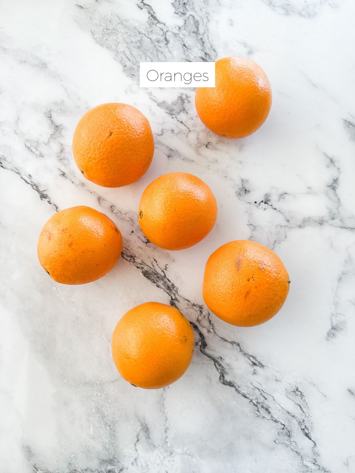 Oranges on white marble bench top. 