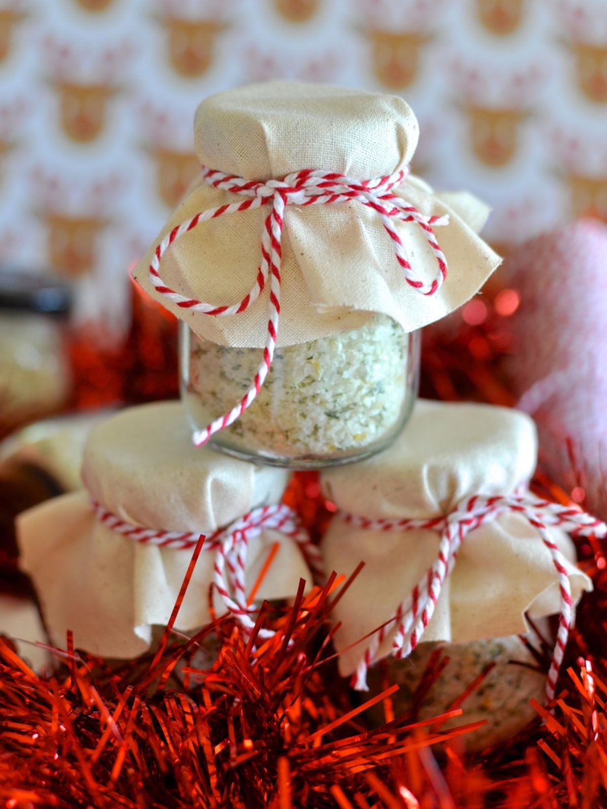 3 jars of lemon and rosemary salt in stack with red tinsel.