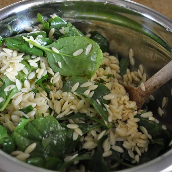 Making risoni salad - mixing in the herbs and spinach