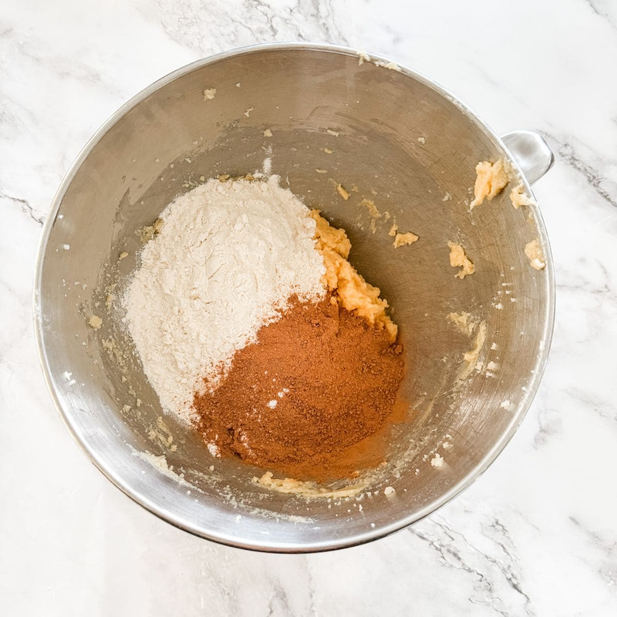 Combined butter, sugar and egg in silver mixing bowl with flour and Milo on top. 