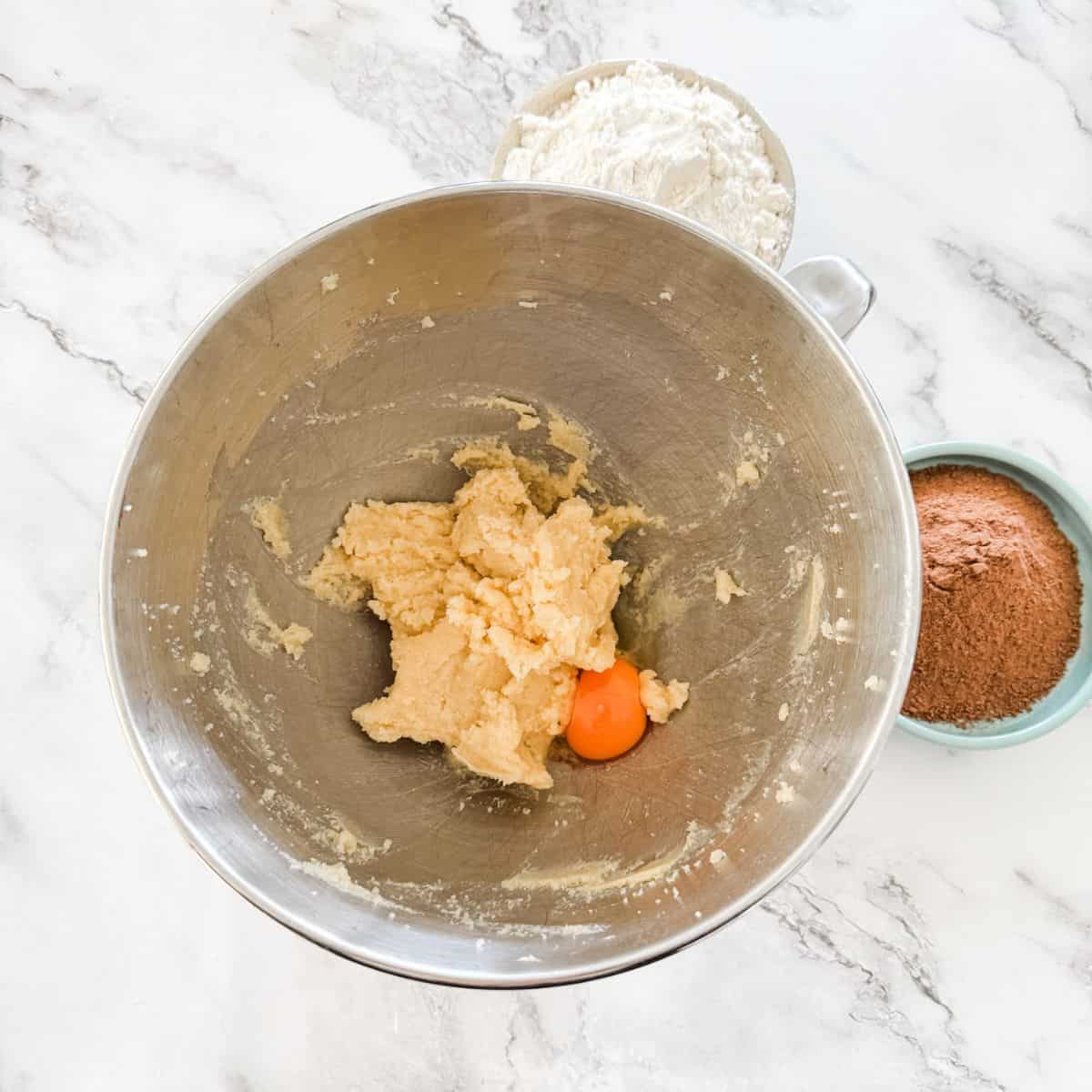 Butter and sugar combined with and egg in a silver mixing bowl. 