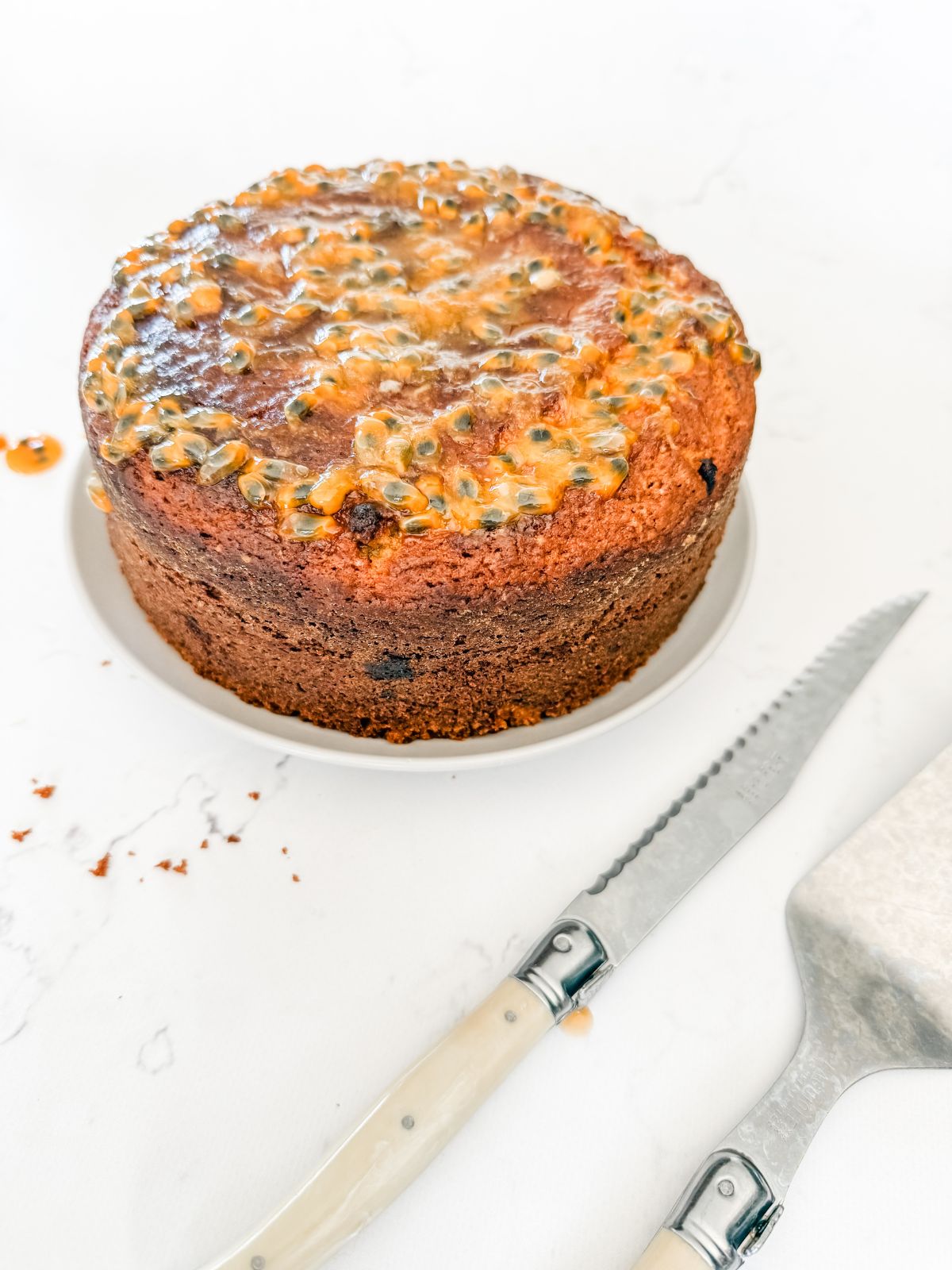 Passionfruit cake on a white plate with a cake knife. 