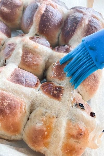 Best soft fluffy hot cross buns recipe (with sourdough) being brushed with glaze for hot cross buns