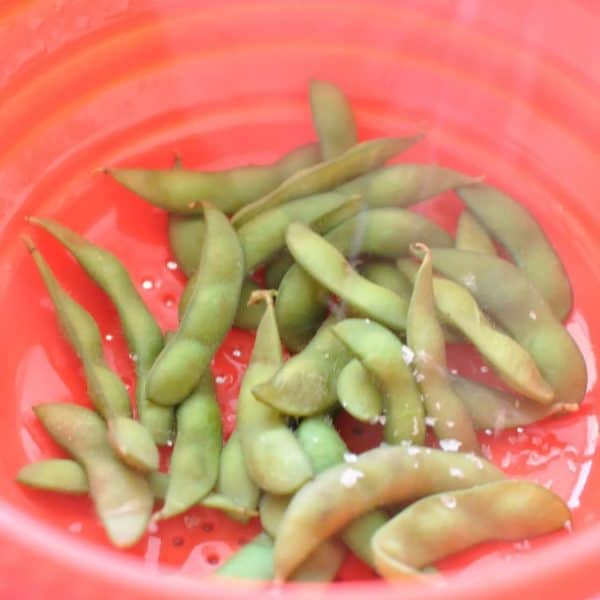 Cooked edamame beans in a red drainer
