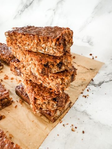 Stack of 4 homemade muesli bars on white marble benchtop.