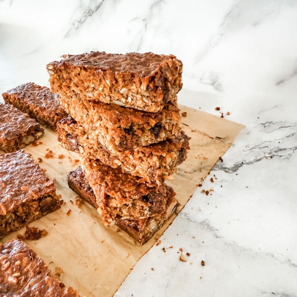 Stack of 4 homemade muesli bars on white marble benchtop.