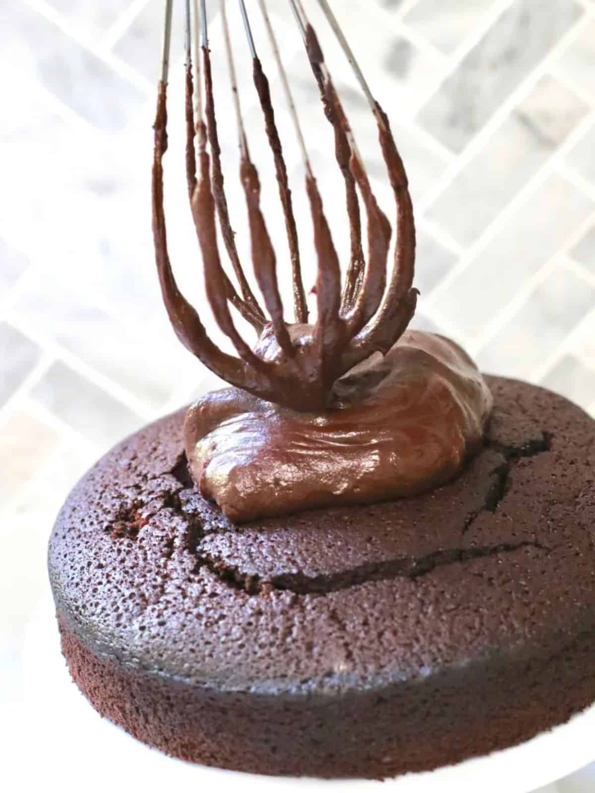 Chocolate fudge icing being added to a chocolate cake