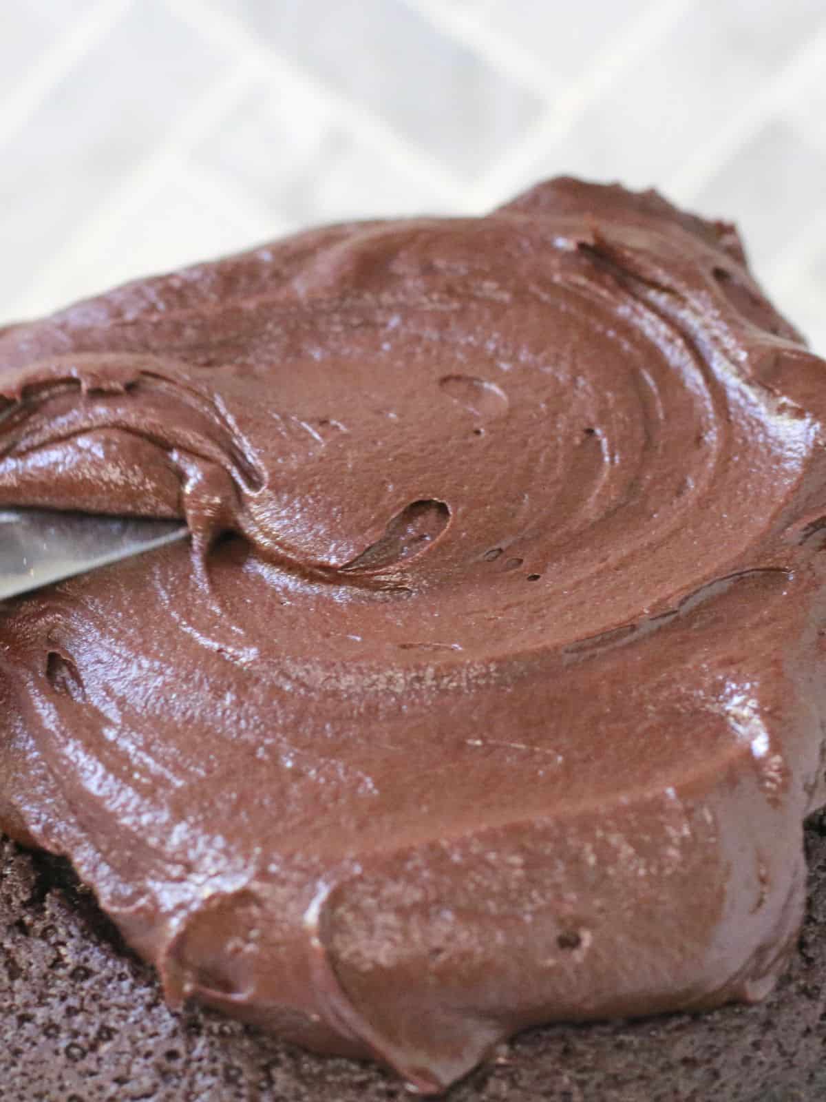 Chocolate fudge icing being spread on a cake