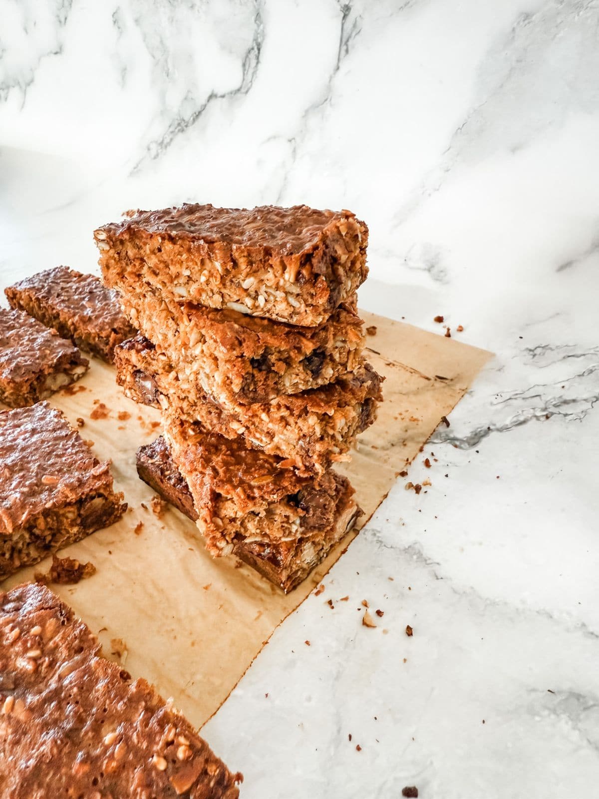 Stack of 4 homemade muesli bars on white marble benchtop. 