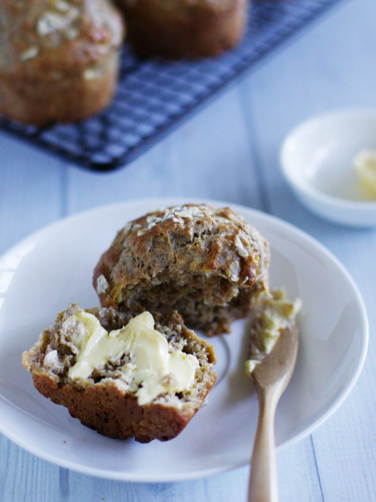 Banana oat muffin cut in half spread with butter.