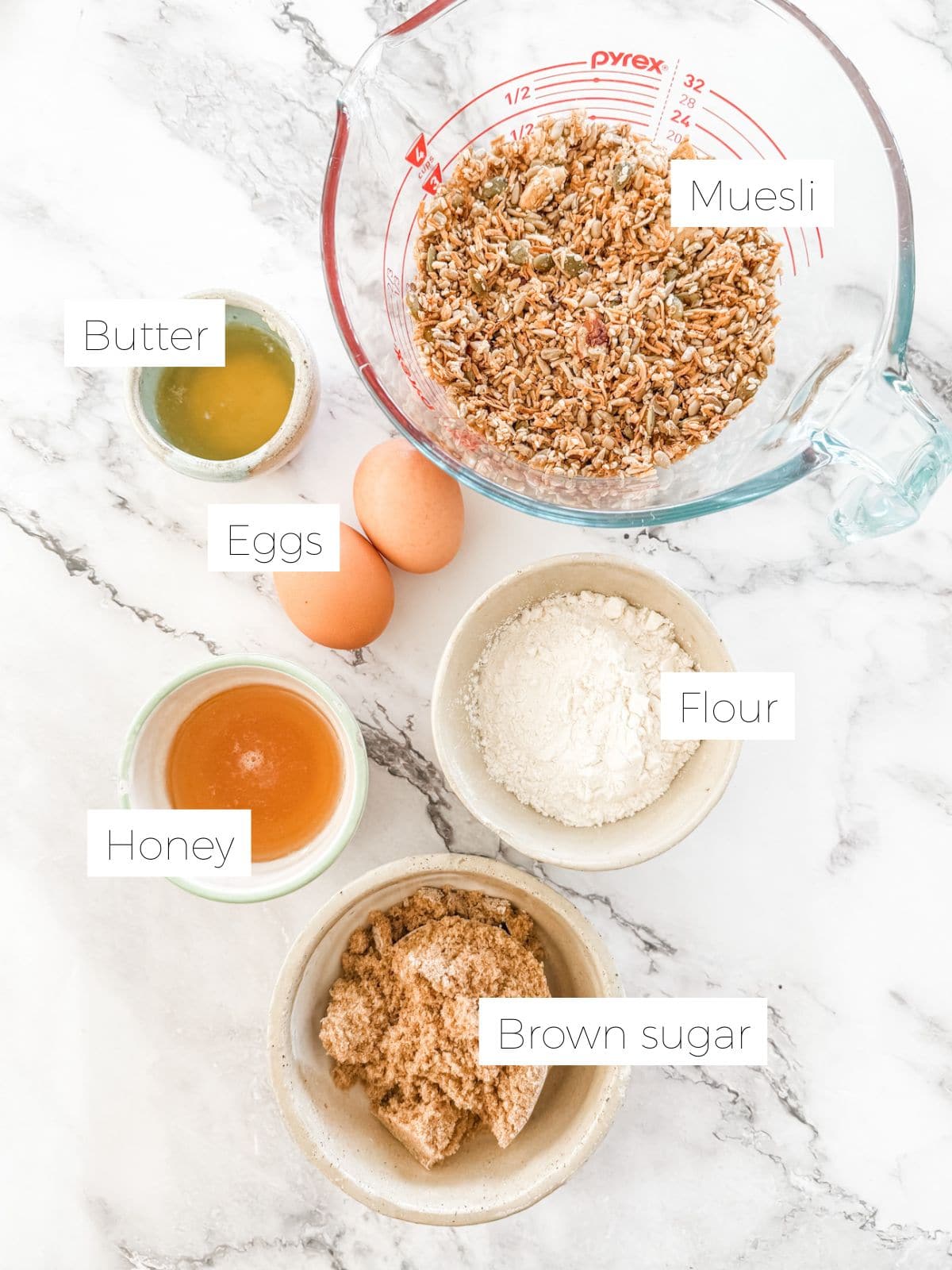 Ingredients in Easy homemade muesli bars - Bowl of muesli, sugar, eggs, butter, sugar & flour & honey. 