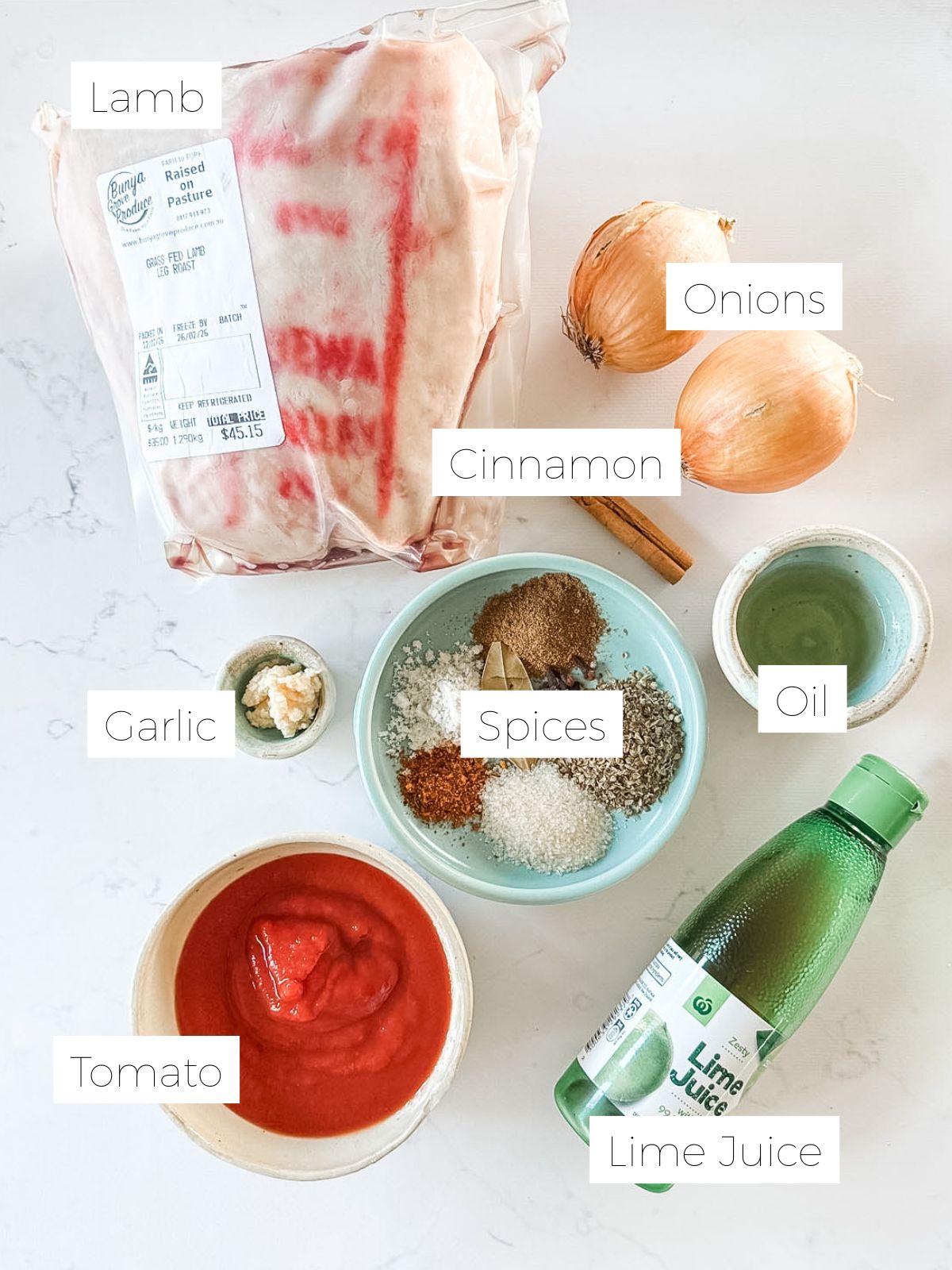 Leg of lamb, bowl of spices, lime juice, 2 onions on white marble bench to make slow cooker Mexican leg of lamb. 