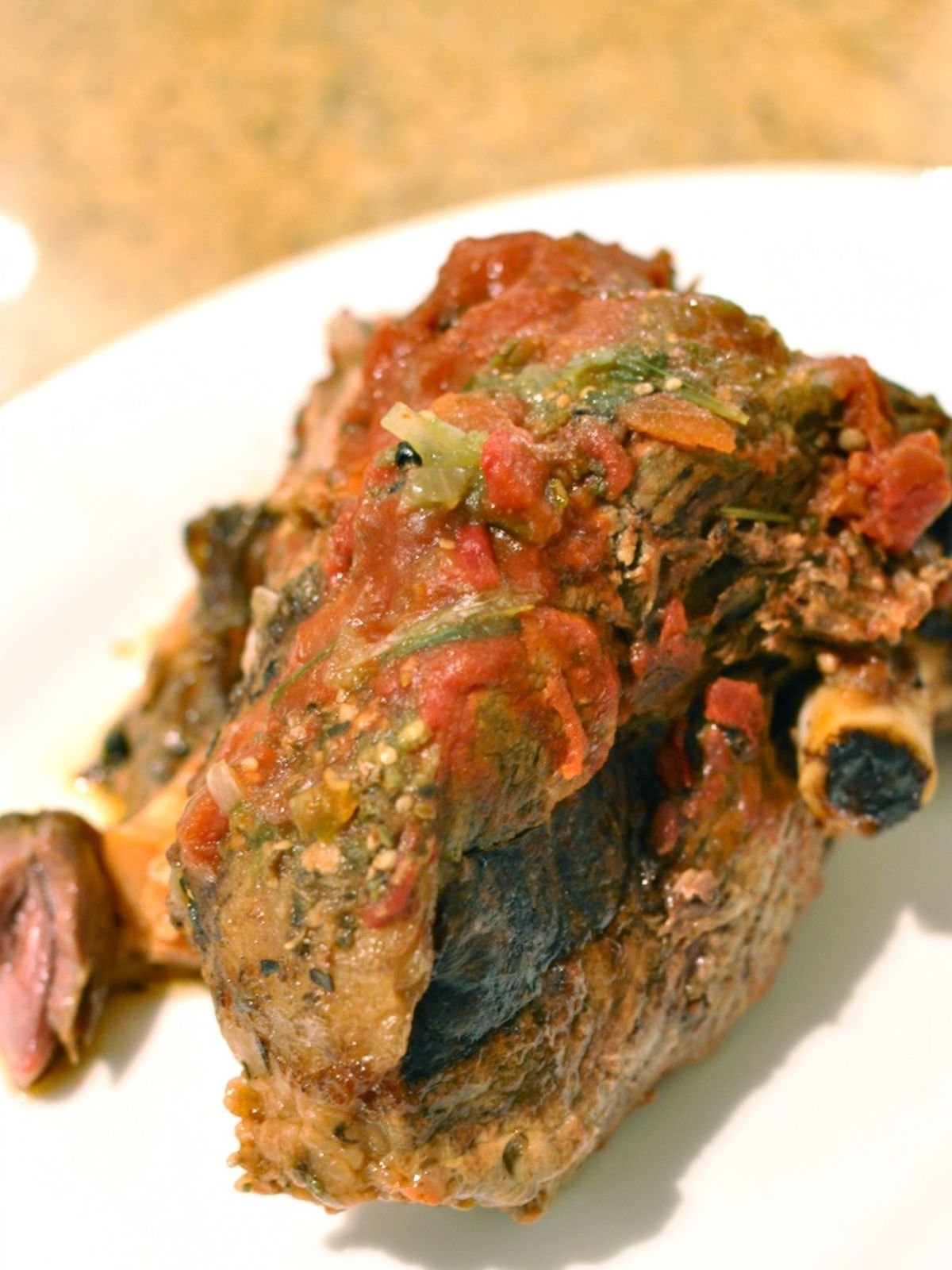 Slow cooked Mexican leg of lamb on a white plate ready to shred. 