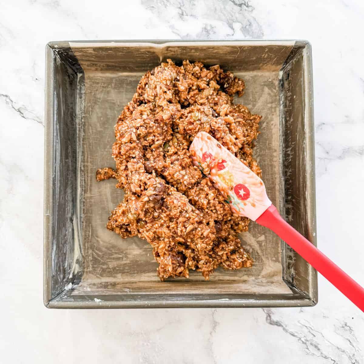 Spreading muesli mixture into prepared tin. 