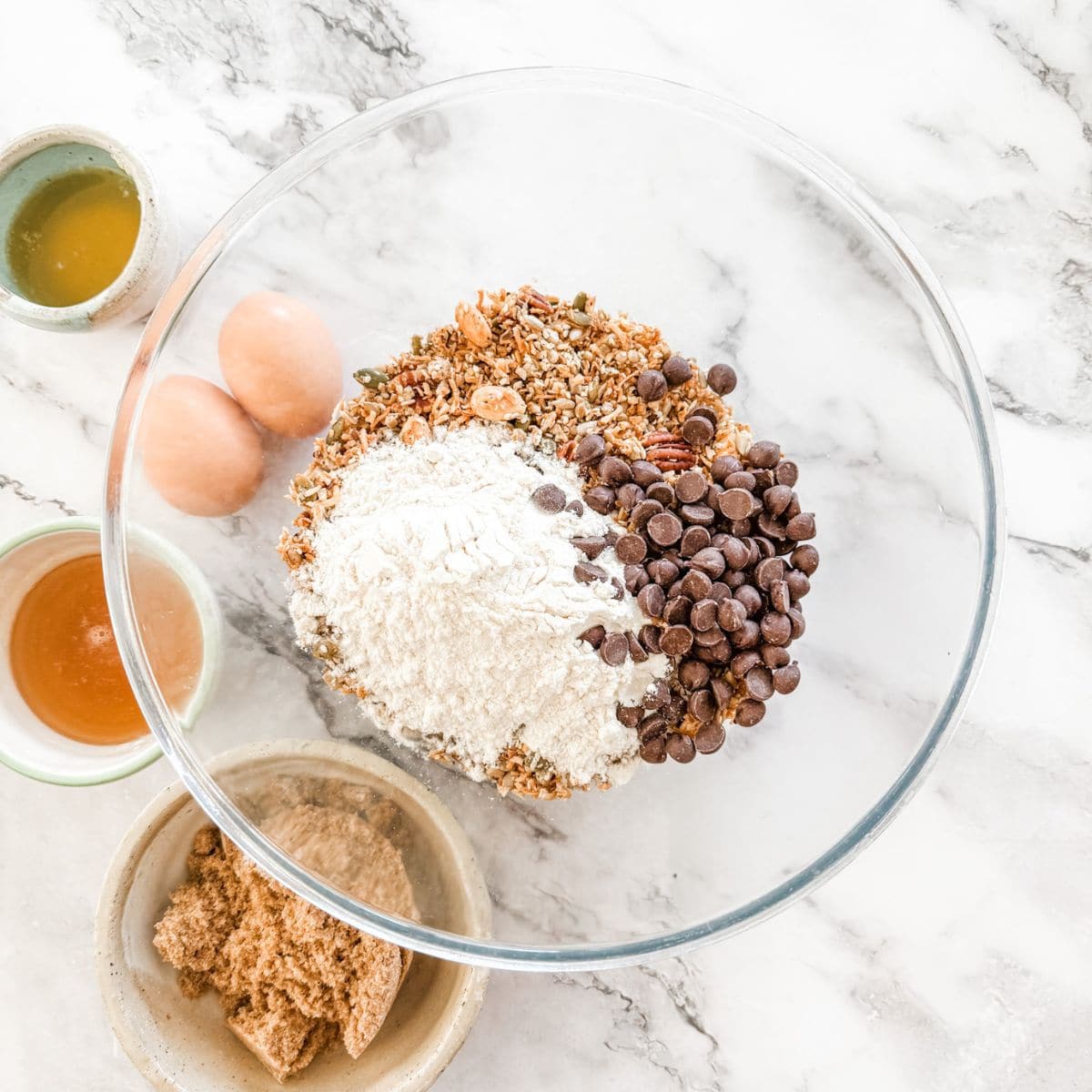 Muesli and flour and chocolate chips in a glass bowl.