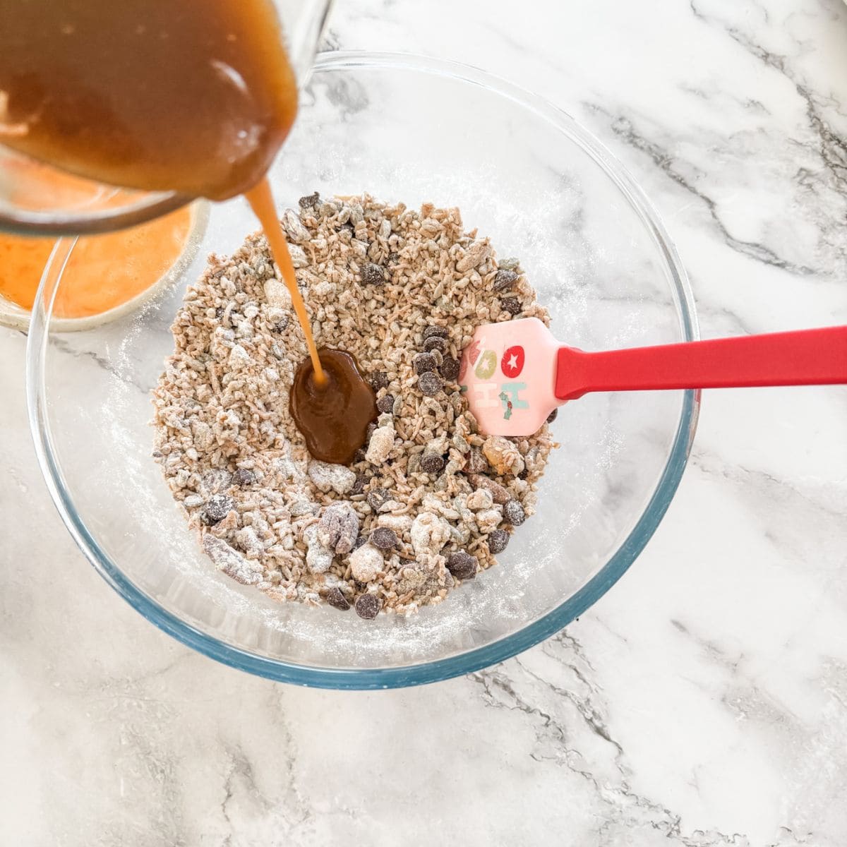 Pouring melted butter and sugar over muesli & flour in glass bowl. 